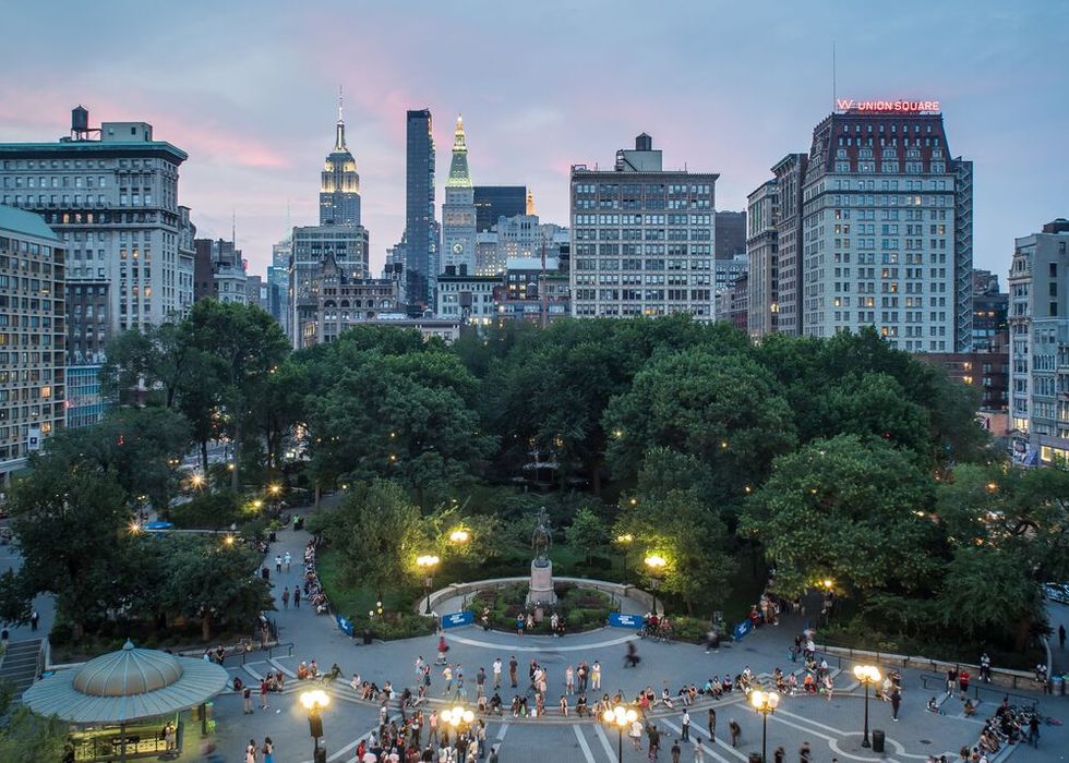 a park with trees and buildings in the background with union square manhattan in the background