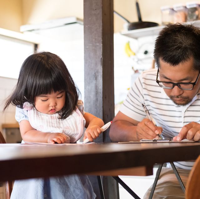 japanese father and daughter filling out paperwork on kitchen table