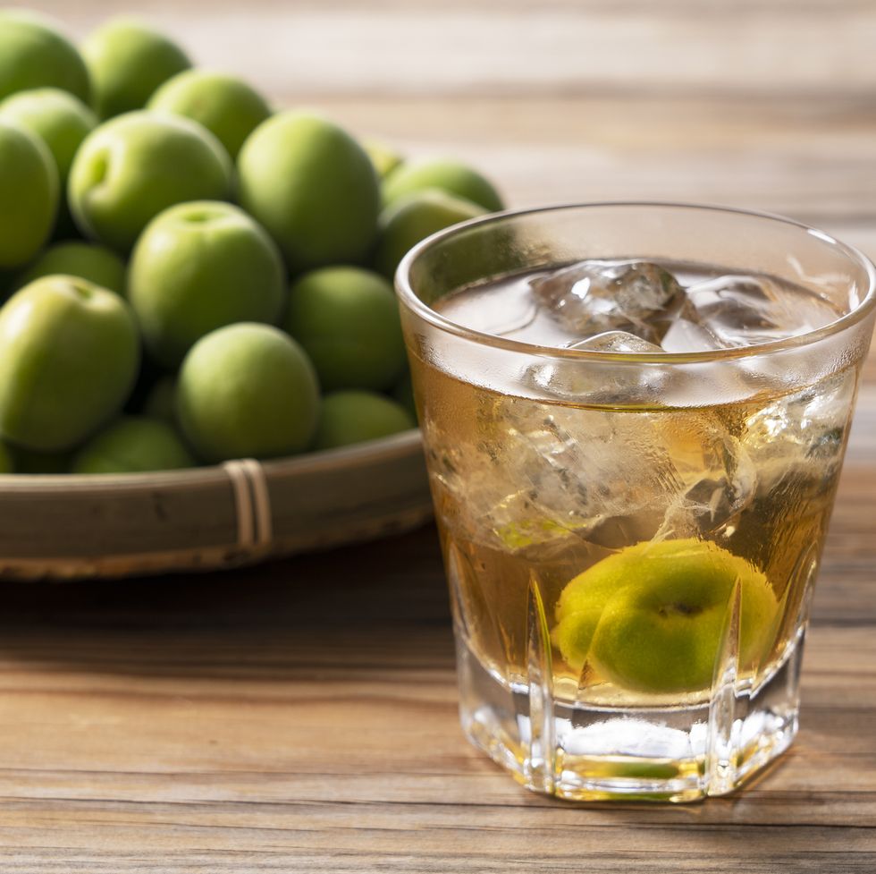 japanese plum wine and unripe plums on a wooden background