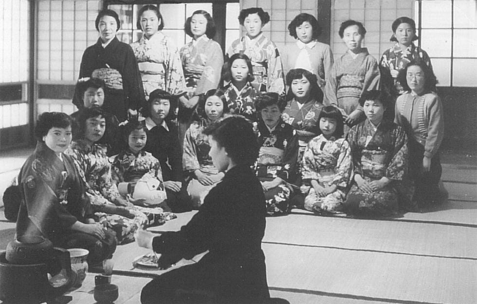 De zesjarige Koizumi zittend en derde van links wordt tijdens een theeceremonie omringd door haar vele zusjes terwijl ze een speelgoedbeest vasthoudt Haar lerares staat links achter haar in de rij achter het gezin Koizumi bewaarde deze foto 66 jaar lang omdat de mensen anders misschien zouden twijfelen aan mijn verhaal dat ik al op zesjarige leeftijd wilde uitzoeken wat ik de rest van mijn leven zou gaan doen