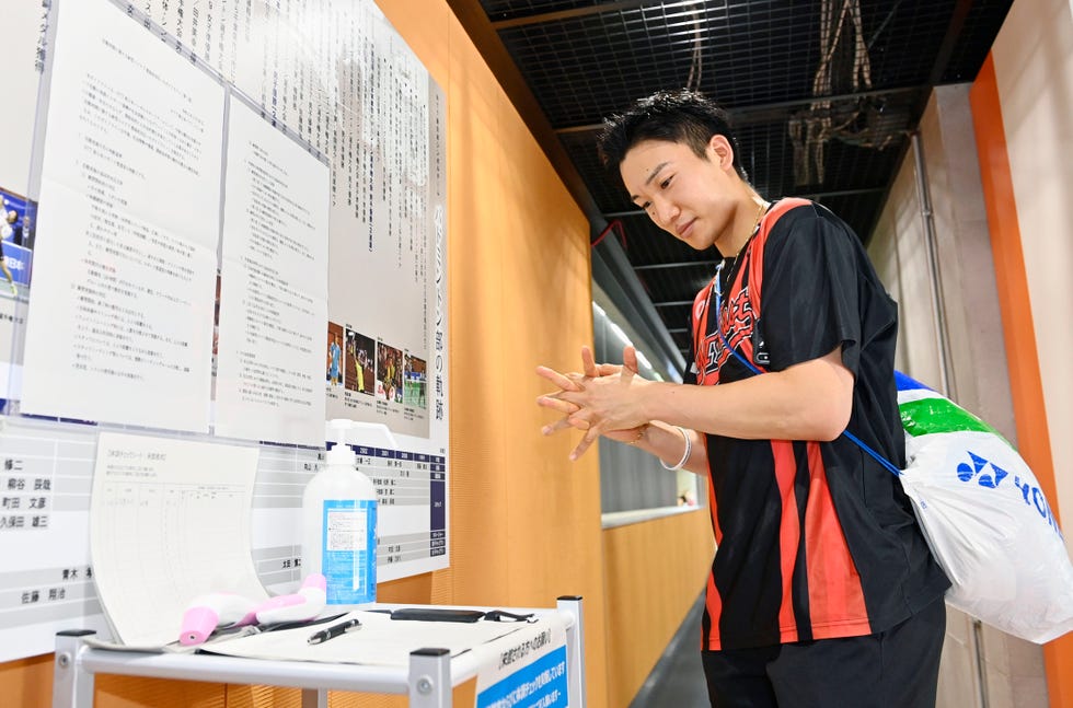 el jugador de bádminton japonés kento momota se desinfecta las manos antes de acceder a una sesión de entrenamiento en tokio