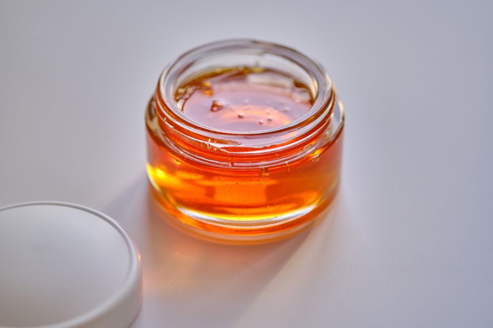a jar with sugaring wax for depilation with a white lid stands on a white surface