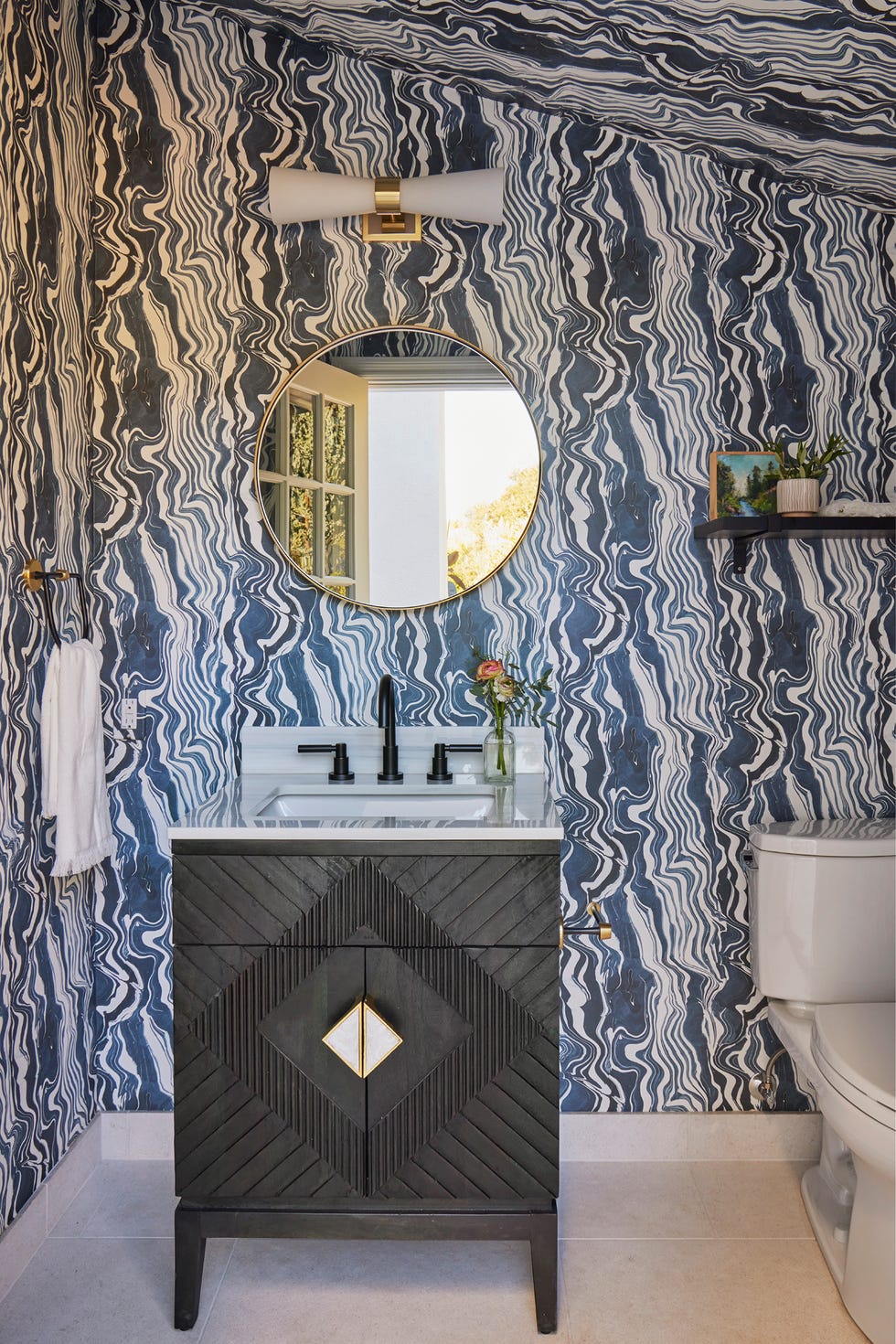 baño con mueble negro de estilo art déco y papel pintado con motivos abstractos azules