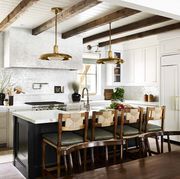 white kitchen with wood beams and green chairs