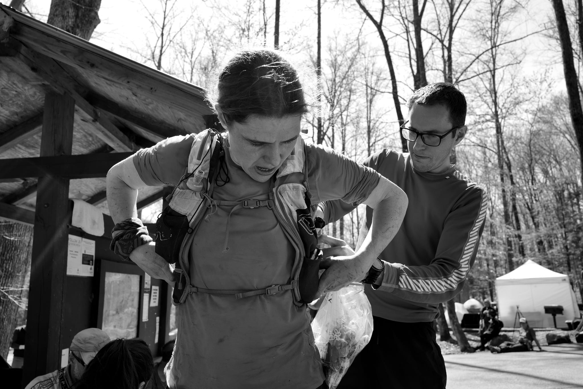 a black and white photo of a runner being helped to put on a running vest