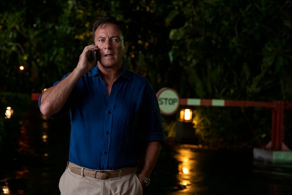 a man engaged in a phone conversation at a dimly lit location with a stop sign in view