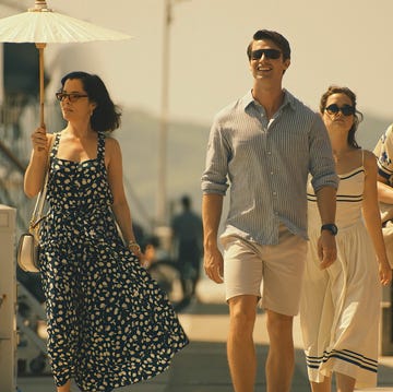 group of people walking along a sunny promenade with a white parasol group of people walking along a sunny promenade with a white parasol