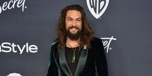 jason momoa poses at an event wearing a green velvet jacket
