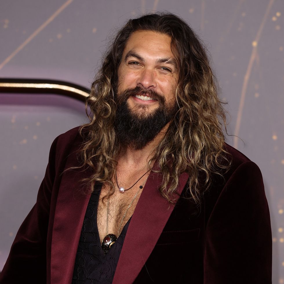 jason momoa smiles on the red carpet at a movie premiere