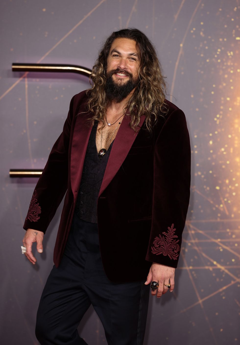 jason momoa smiles on the red carpet at a movie premiere