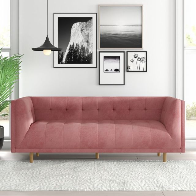 a blush velvet couch in front of a gallery wall