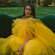 jazmine in yellow tulle dress on a green couch outside