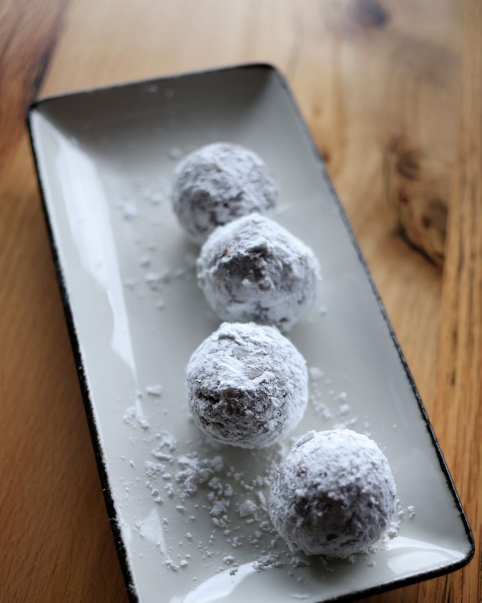 tray of chocolate bourbon balls rolled in powdered sugar on a wooden table