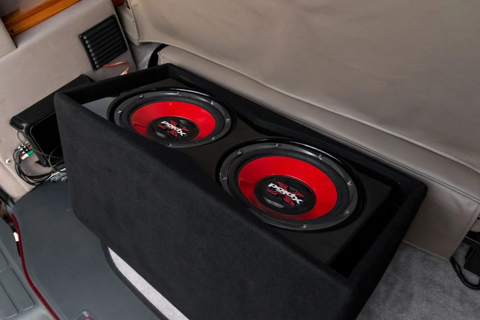 the interior of a chevrolet express conversion van, showing off a pair of aftermarket subwoofers