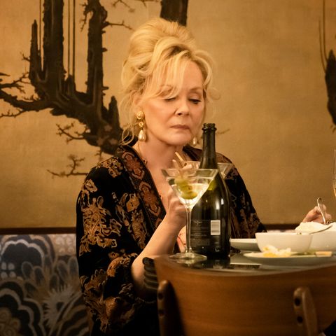 jean smart in a animal print blouse drinking a martini