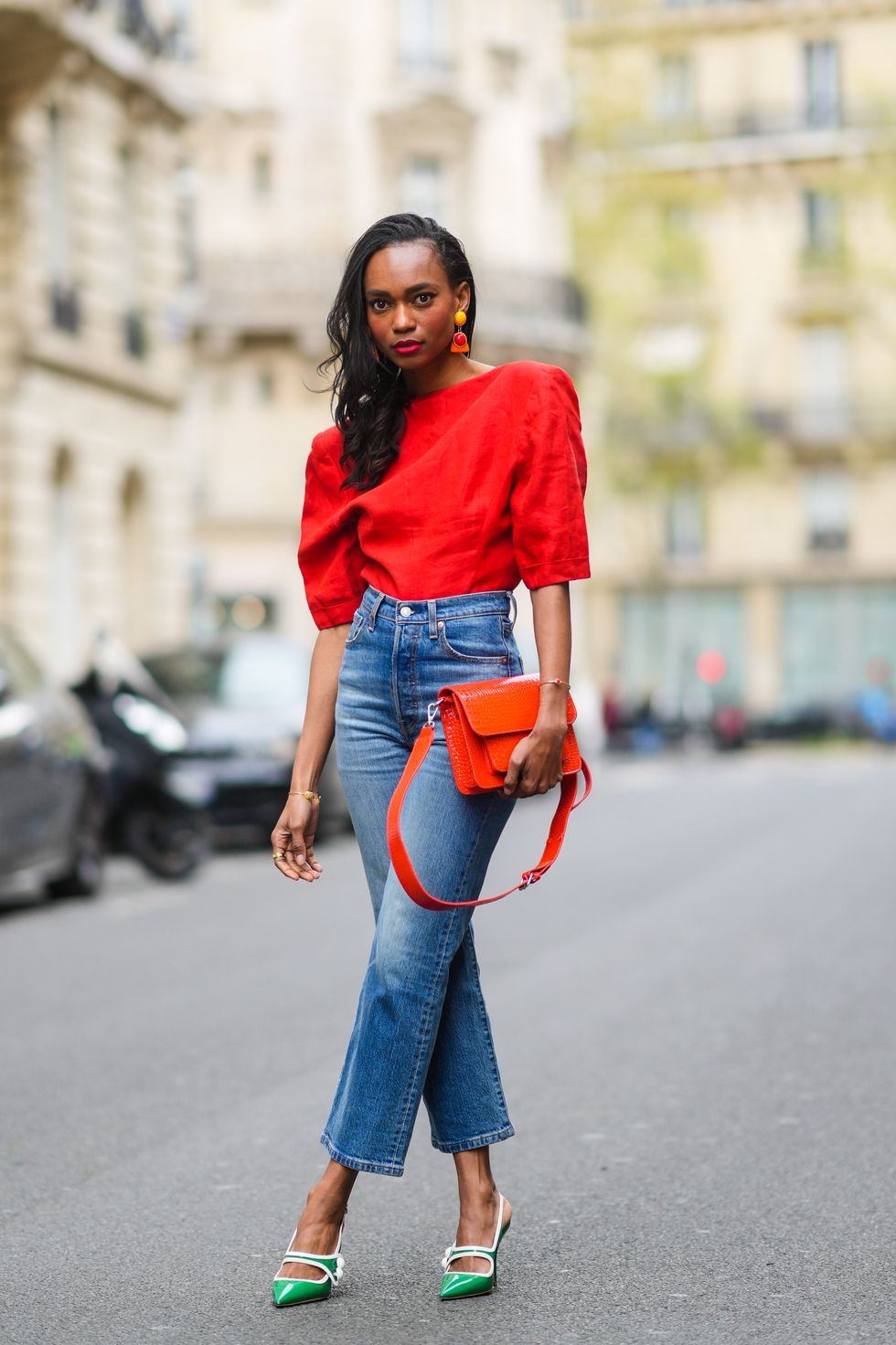 paris, france   april 18 emilie joseph infashionwetrust wears a red vintage linen power shoulder top worn backwards with plunging neckline in the back, blue denim high rise straight ribcage jeans from levis, green two toned patent leather pointy sling back sandals  pumps from miumiu, a red vegan embossed leather bag from hvisk, clip on vintage colorblock ceramic earrings, on april 18, 2021 in paris, france photo by edward berthelotgetty images