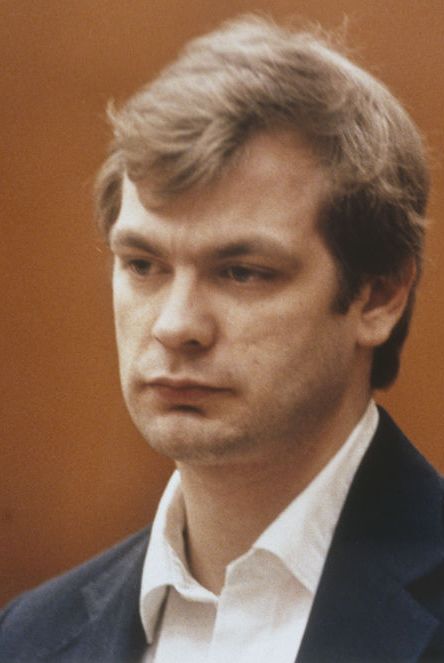jeffrey dahmer wearing a blue suit and white shirt and looking out of frame