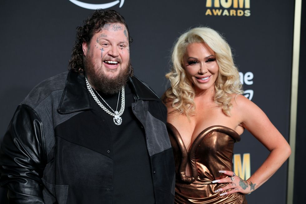 jelly roll and wife bunnie xo smiling for red carpet photographers at an awards show