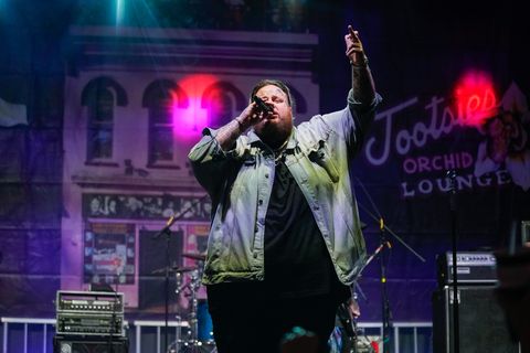 jelly roll holding a microphone while performing on stage