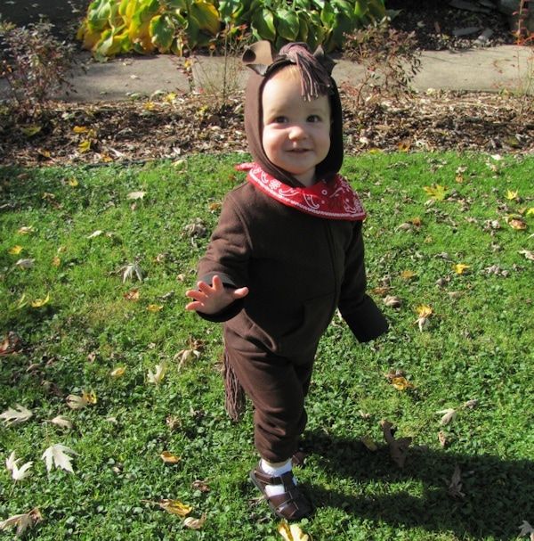 child dressed as horse in brown hooded sweatshirt and pants with a red bandana around neck the hood has a mane made of yarn and brown felt ears