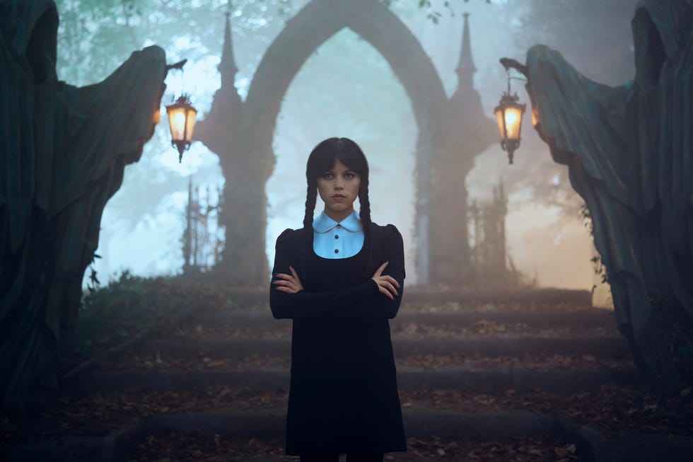 a girl stands confidently on stone steps in a misty setting with gothic architecture in the background