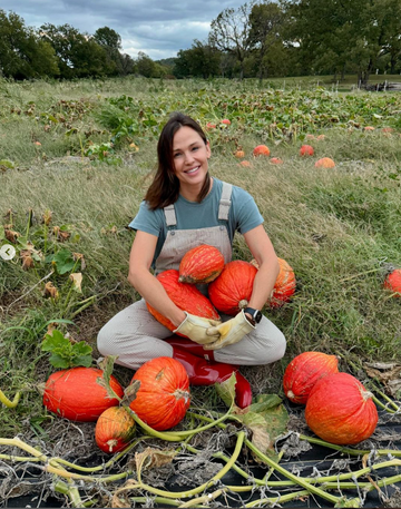 person surrounded by pumpkins in a field