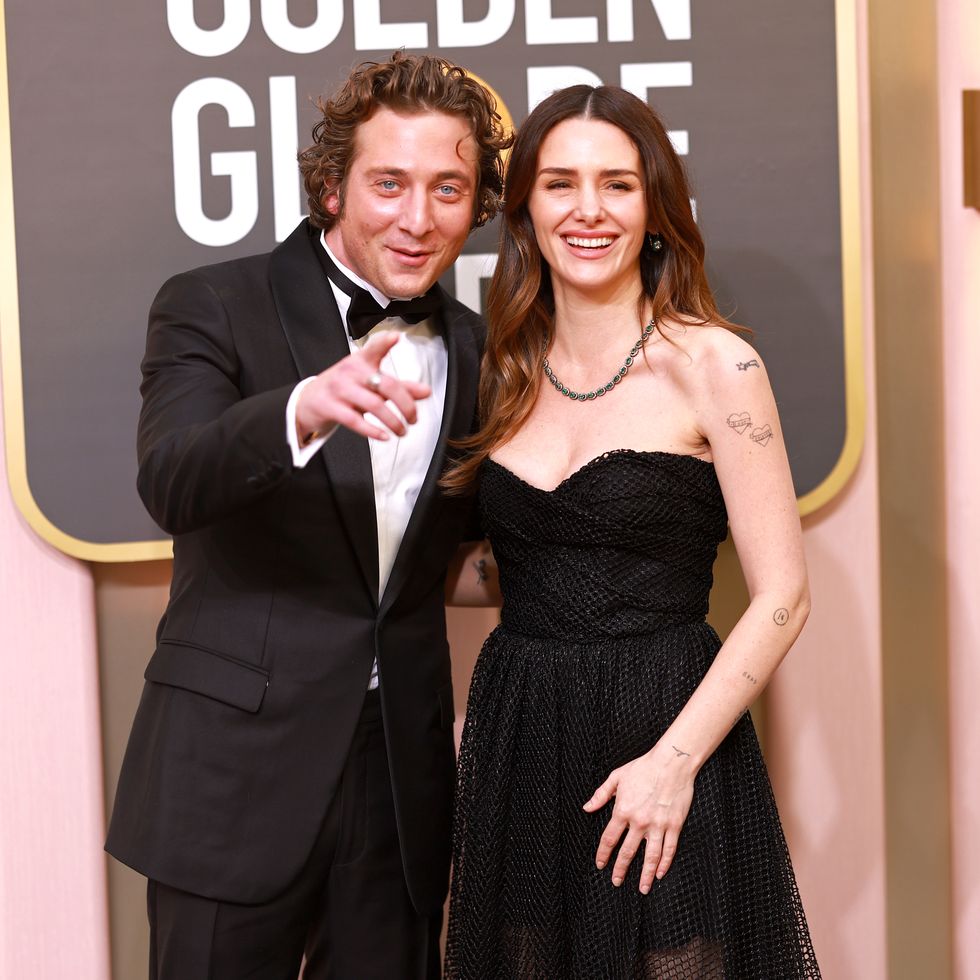 jeremy allen white, wearing a black tuxedo, and addison timlin, wearing a black dress, pose for a photo in front of a golden globes sign