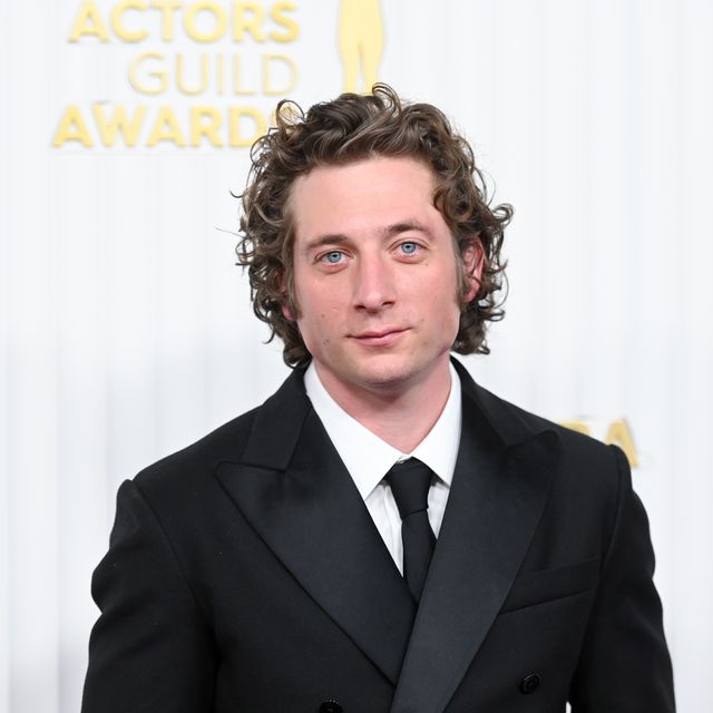 jeremy allen white looks at the camera with a slight smile, he wears a black suit and tie with a white collared shirt
