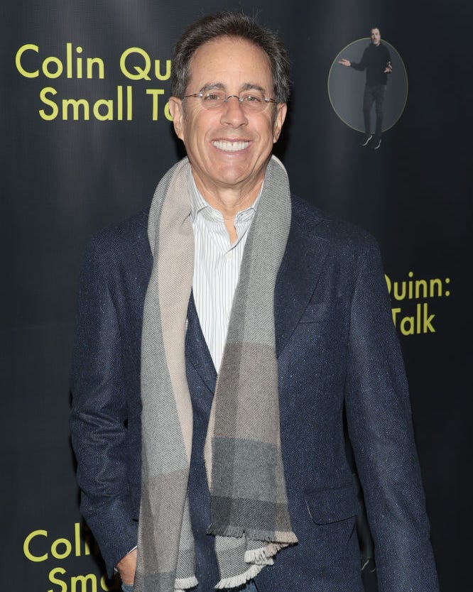 Jerry Seinfeld at premiere of Colin Quinn: Small Talk in New York City jerry seinfeld smiling for a photo at a premiere event wearing a suit jacket and scarf