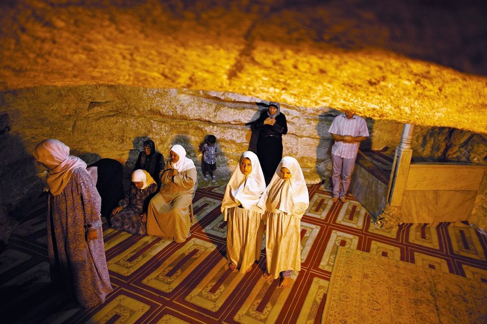 Islamitische bedevaartgangers bidden in een ruimte onder de heilige Rotskoepel Moslims geloven dat hun profeet van deze rots opsteeg naar de hemel