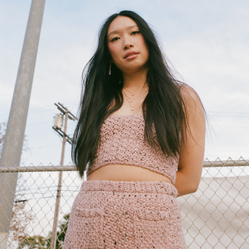 jess hong posing in a crochet pink top and skirt