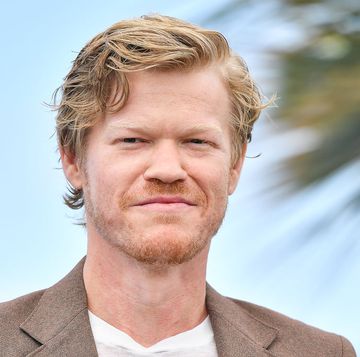 actor jesse plemons smiling for a photo with palm leaves in the background