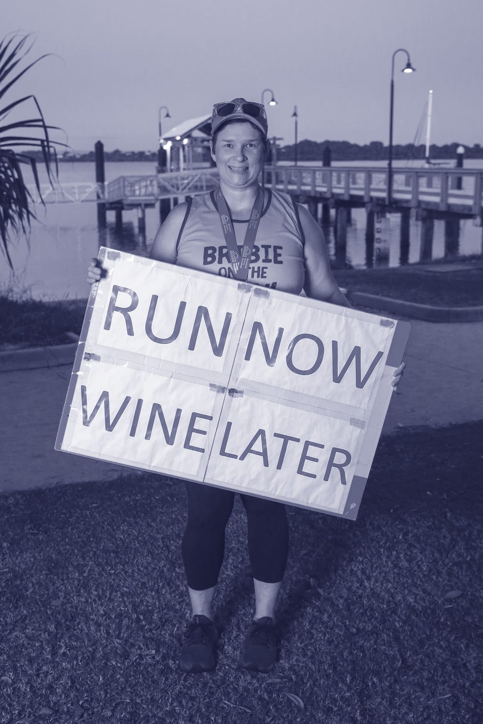 smiling runner standing with a sign beside the coast
