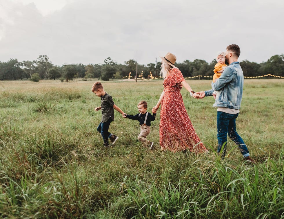 kinderen lopen met vader en moeder aan de hand door het gras