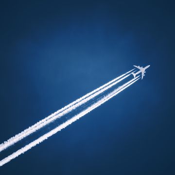 a jet vapour trail across a dark blue sky