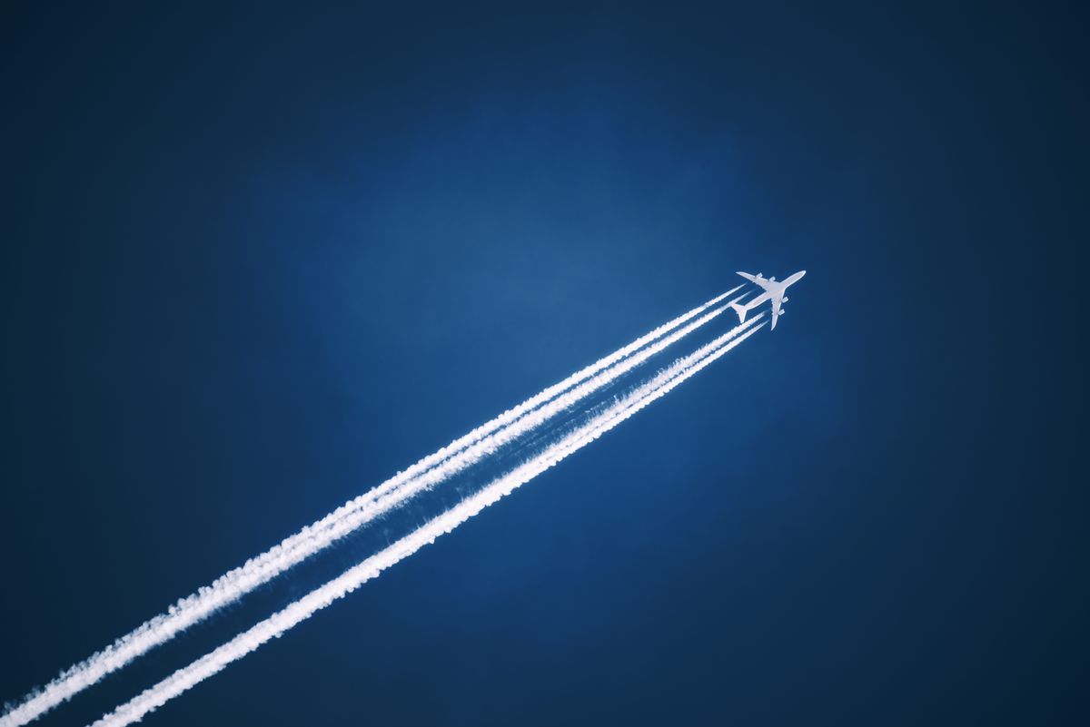 a jet vapour trail across a dark blue sky