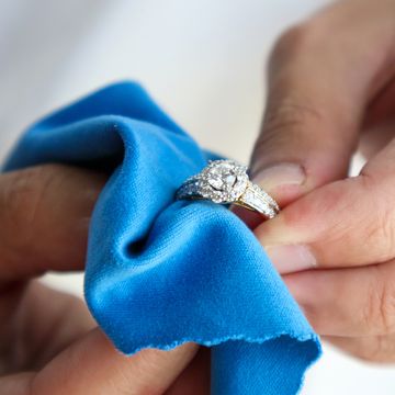 hands cleaning diamond ring with microfiber cloth
