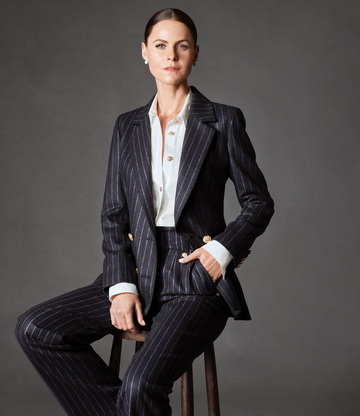a person seated on a stool wearing a pinstripe suit and a white shirt