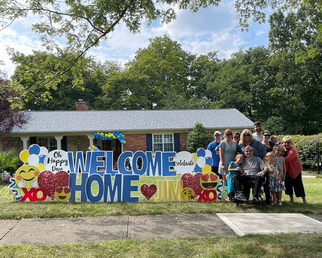 jim leblond and family with welcome home sign outside of their house