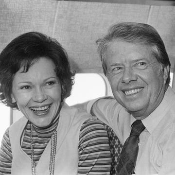 jimmy carter and rosalynn carter smile and look past the camera while sitting on an airplace