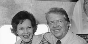 jimmy carter and rosalynn carter smile and look past the camera while sitting on an airplace
