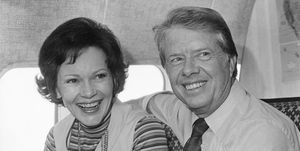 jimmy carter and rosalynn carter smile and look past the camera while sitting on an airplace