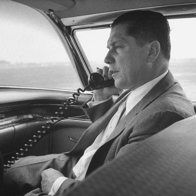 Teamsters boss Jimmy Hoffa using a telephone in the front seat of his chauffeured car