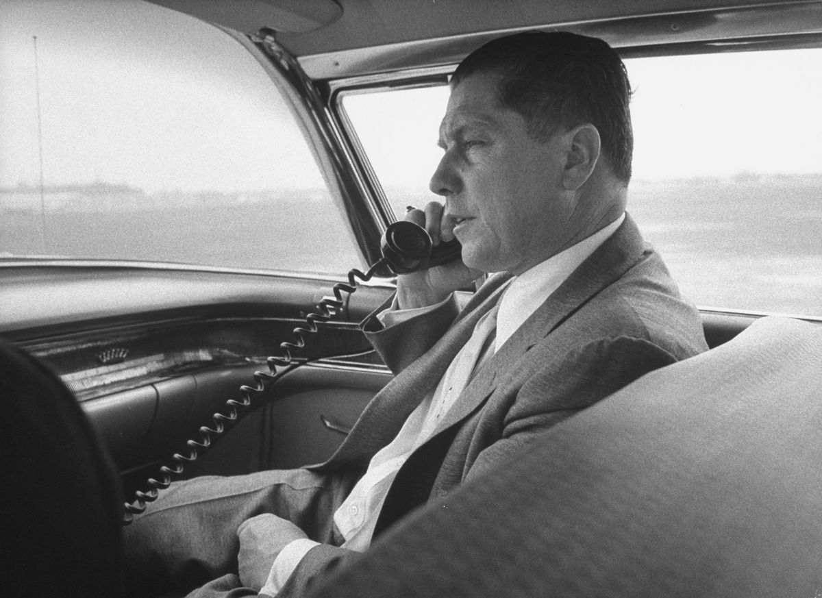 Teamsters boss Jimmy Hoffa using a telephone in the front seat of his chauffeured car