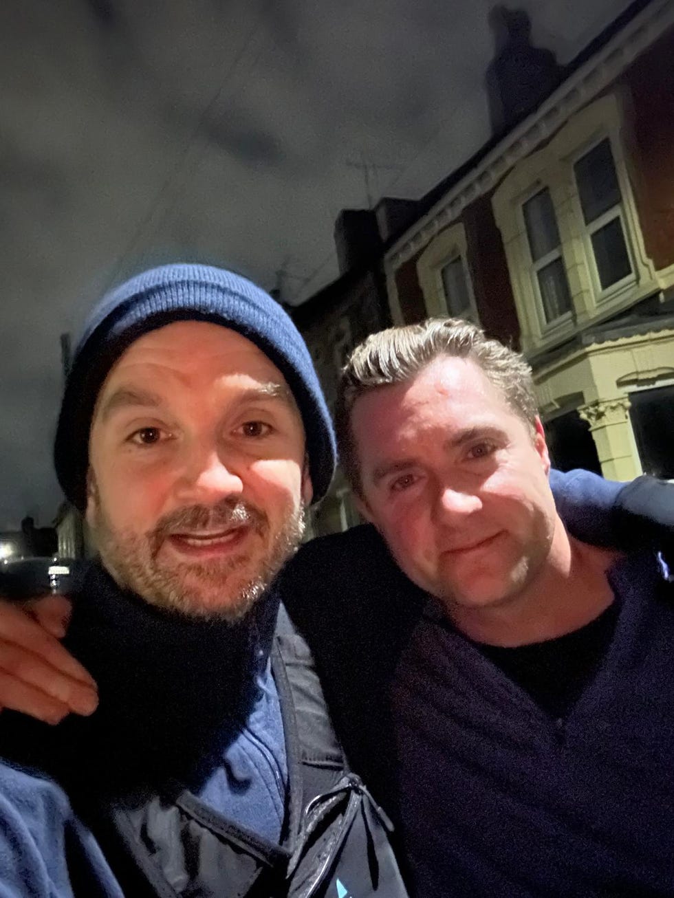 two individuals posing together outdoors at night