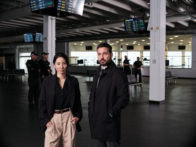 couple standing at an airport terminal with boarding information displays