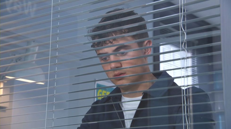 JJ schaut durch ein Krankenhausfenster in Hollyoaks