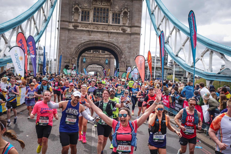 participants running in a marathon beneath a historic bridge with spectators