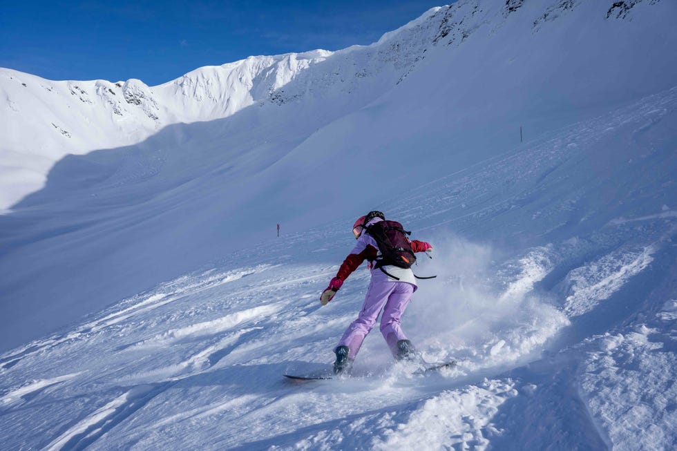 person snowboarding on a snowy slope with mountain backdrop