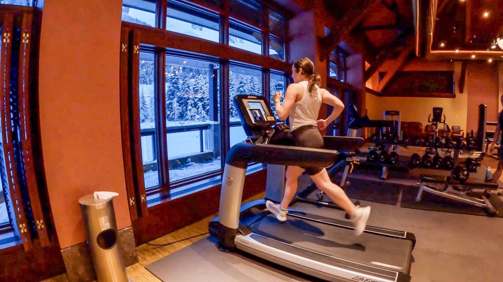 individual exercising on a treadmill in a gym with large windows overlooking a snowy landscape